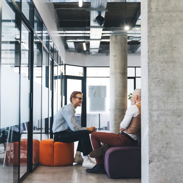 Two men sat on chairs in open office discussing consultancy solutions