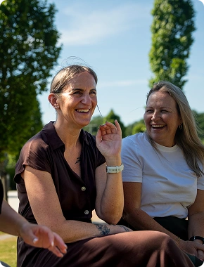Two women laughing outdoors together, showcasing a friendly culture at an insolvency jobs company.