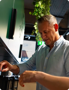 Man making coffee in a modern office break room, part of the team at an insolvency jobs company.
