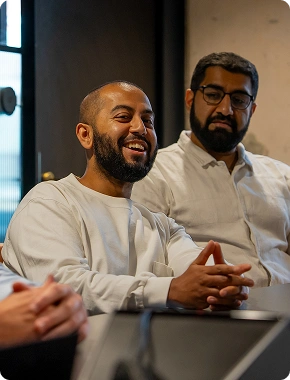 Two men smiling during a meeting, reflecting a positive team culture at an insolvency jobs company.