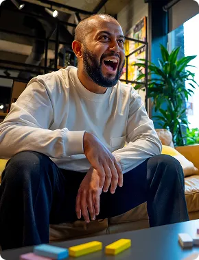 A man laughing during a business consultancy session, sitting on a couch playing games