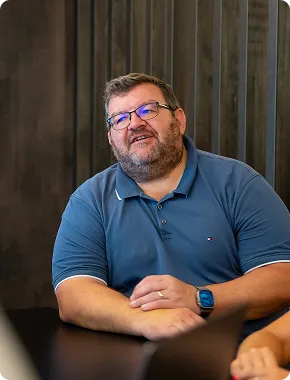 Steve Currie speaking during a business advisory services meeting, seated at a table with hands clasped.
